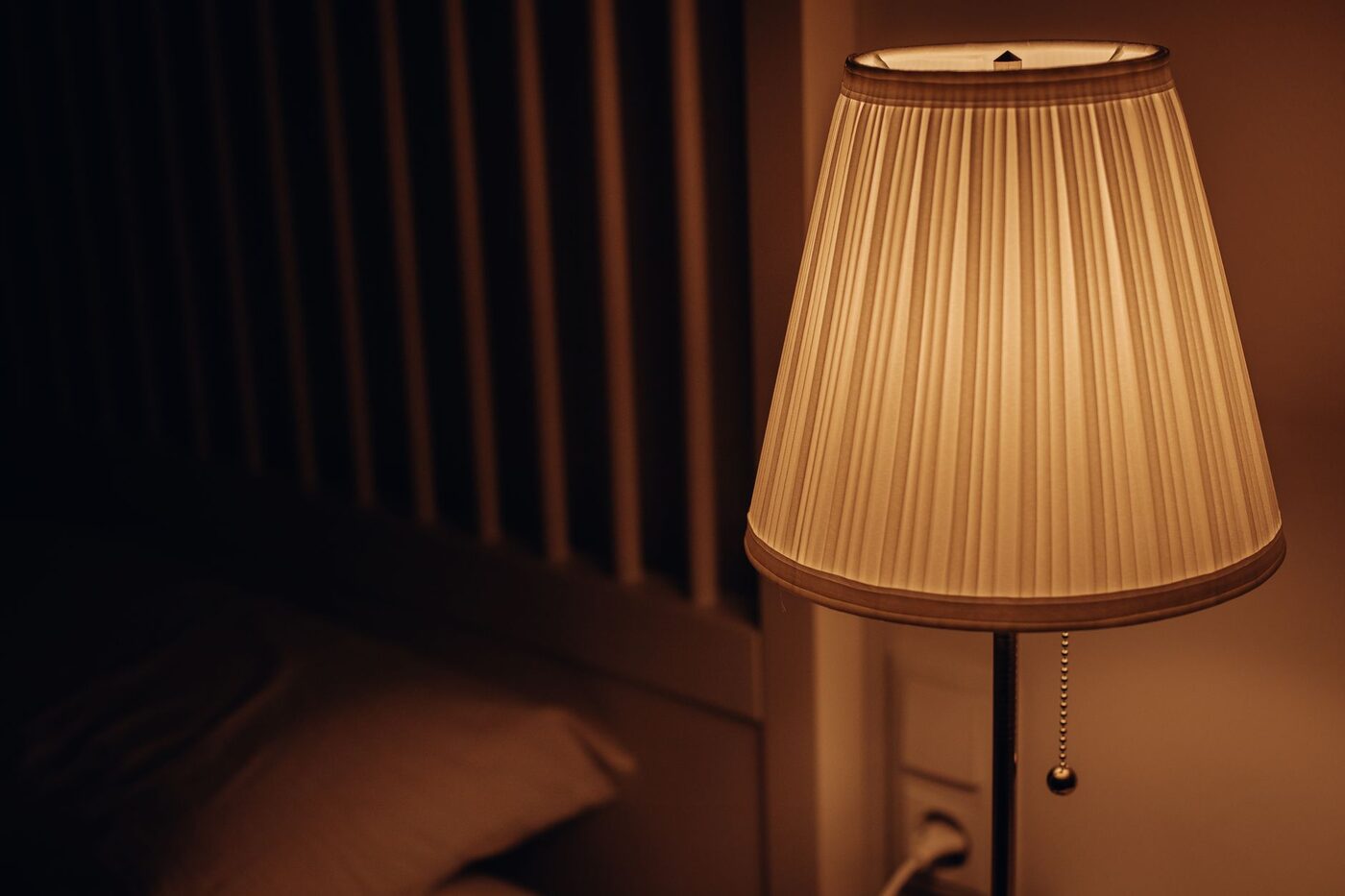 Lampe de chevet allumée dans une chambre sombre, abat-jour en tissu