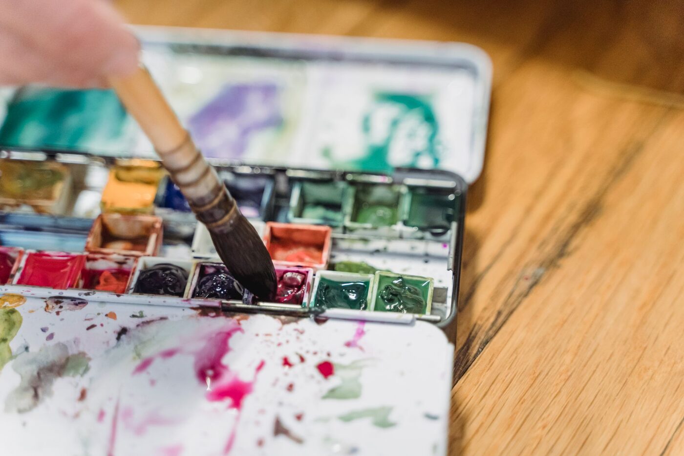Palette d'aquarelle ouverte avec pastilles de couleurs sur une table claire