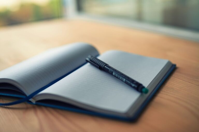 Carnet ouvert aux pages vierges, stylo posé en travers, lumière de fin de journée